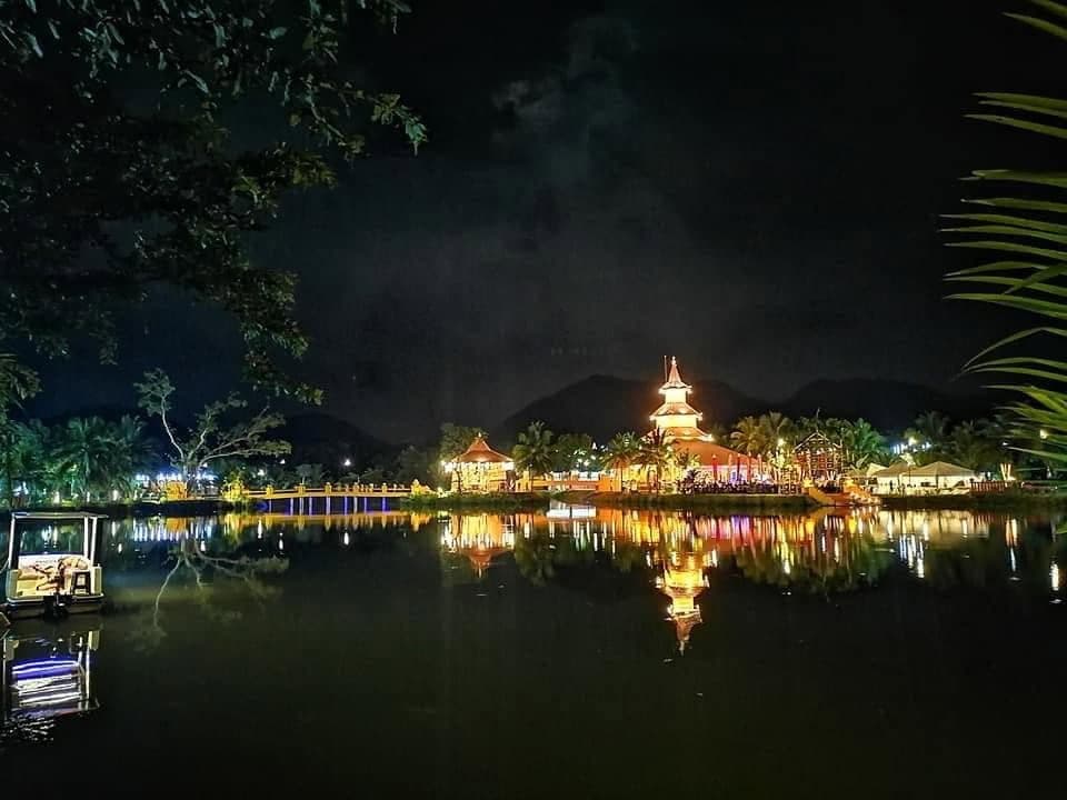 A temple lit up at night, reflected in a still lake
